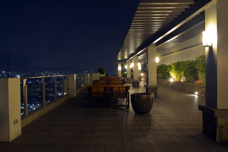 illuminated footpath amidst buildings against sky night